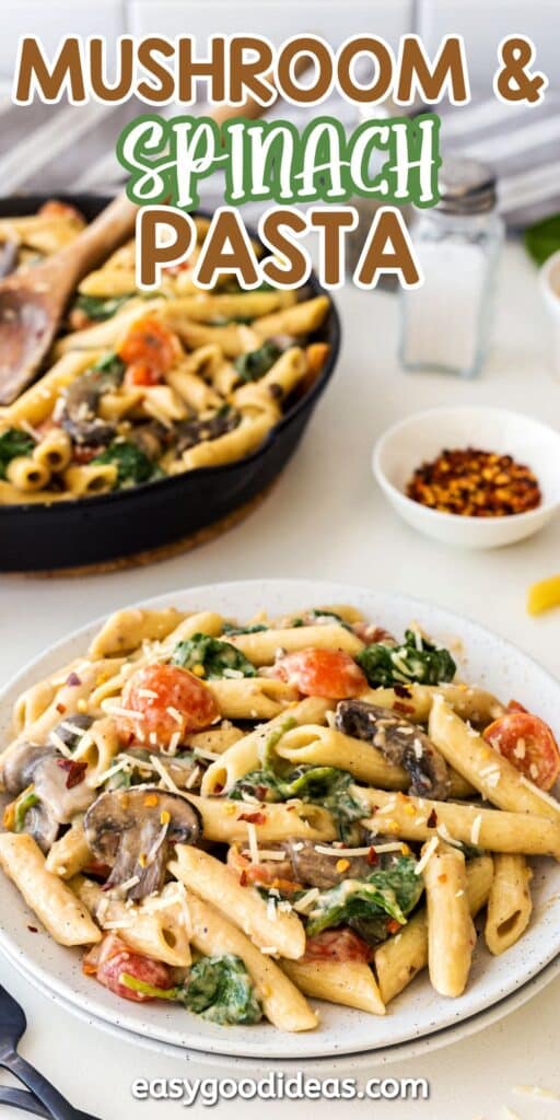 Plate of mushroom and spinach pasta with tomatoes and parmesan, served on a white plate, with a skillet of pasta, a spoon, and small bowls of spices in the background. Text reads Mushroom & Spinach Pasta.