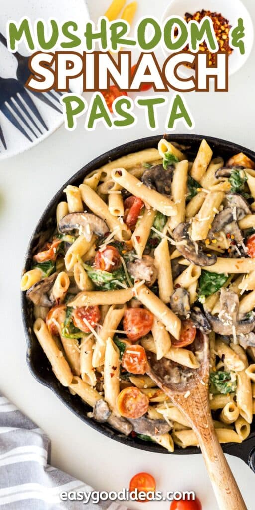 A skillet filled with creamy penne pasta, mushrooms, spinach, and cherry tomatoes, with a wooden spoon. Above, text reads “Mushroom & Spinach Pasta.” A gray napkin and plates are on the table.