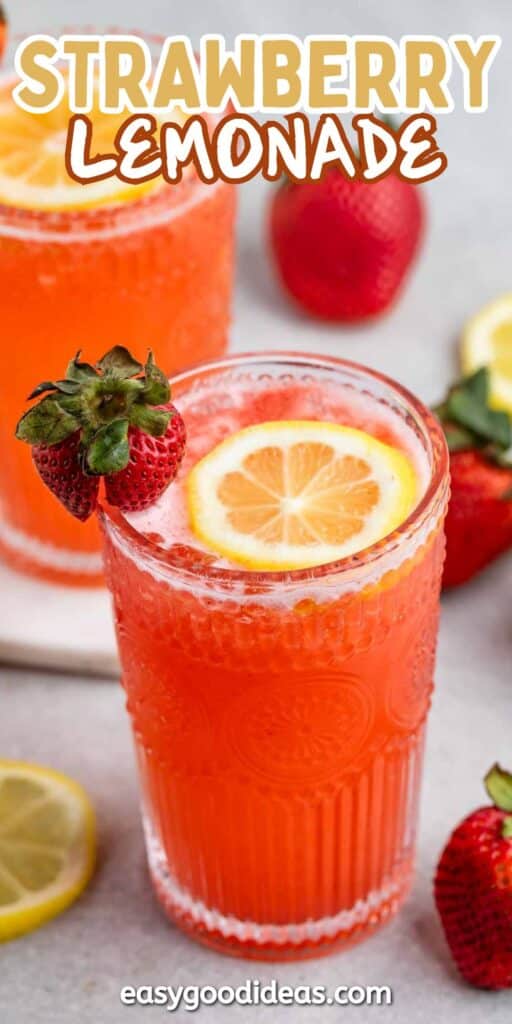 Two glasses of bright red strawberry lemonade garnished with sliced lemon and strawberries. Fresh strawberries and lemon slices are scattered around the glasses, with Strawberry Lemonade written at the top.