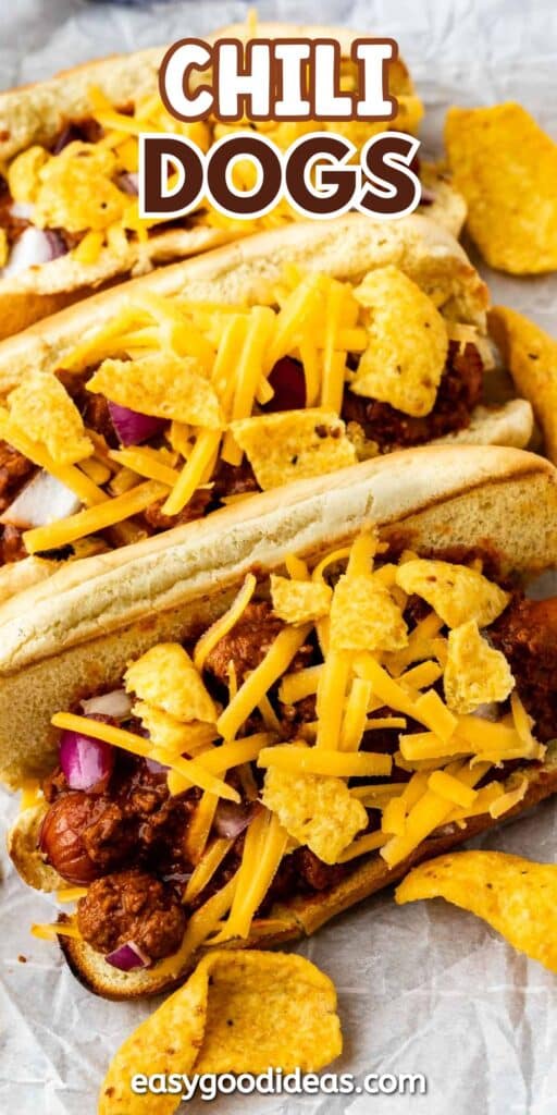 Three chili dogs topped with shredded cheddar cheese, chopped red onions, and crumbled corn chips are arranged on parchment paper. The text CHILI DOGS appears at the top, and easygoodideas.com is at the bottom.
