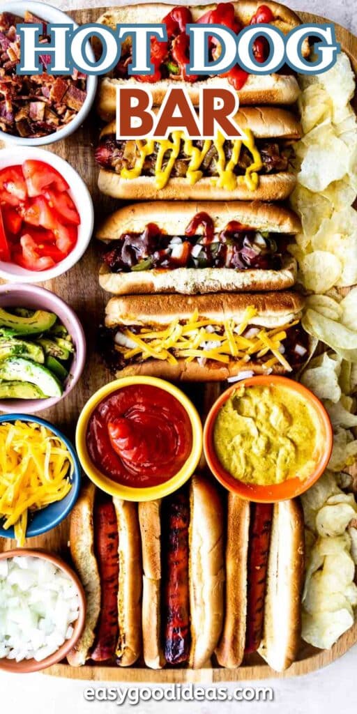 A variety of hot dogs with different toppings, surrounded by bowls of tomatoes, avocado, cheese, onions, ketchup, mustard, and chips. The text HOT DOG BAR appears at the top.