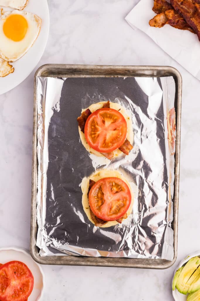 egg topped with bacon and a tomato slice.