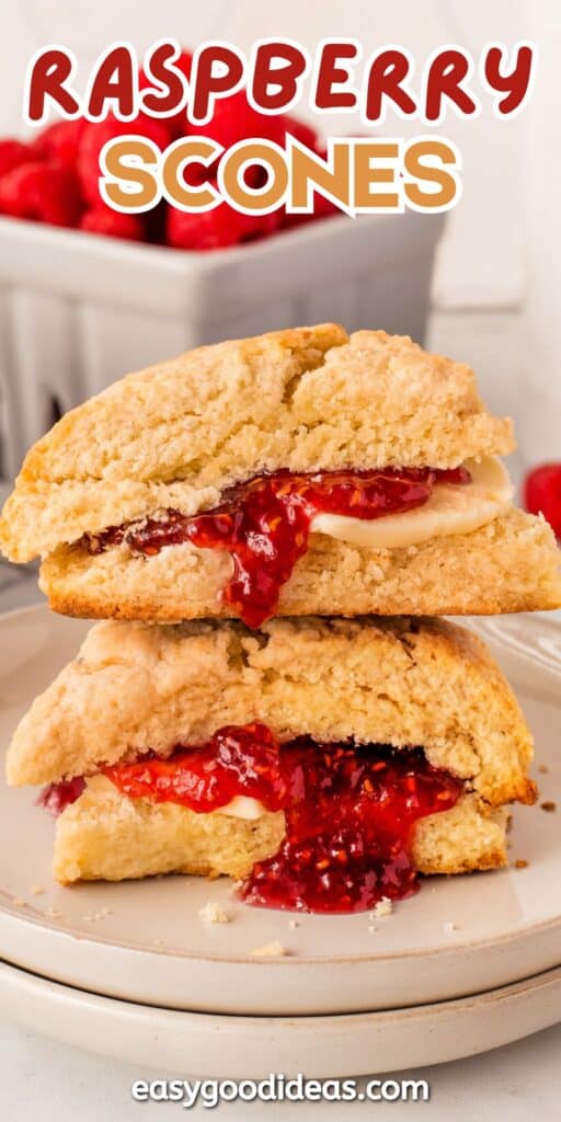 Two golden scones are stacked on a plate, filled with melting butter and vibrant raspberry jam. Fresh raspberries are visible in a dish in the background. Text reads Raspberry Scones at the top.