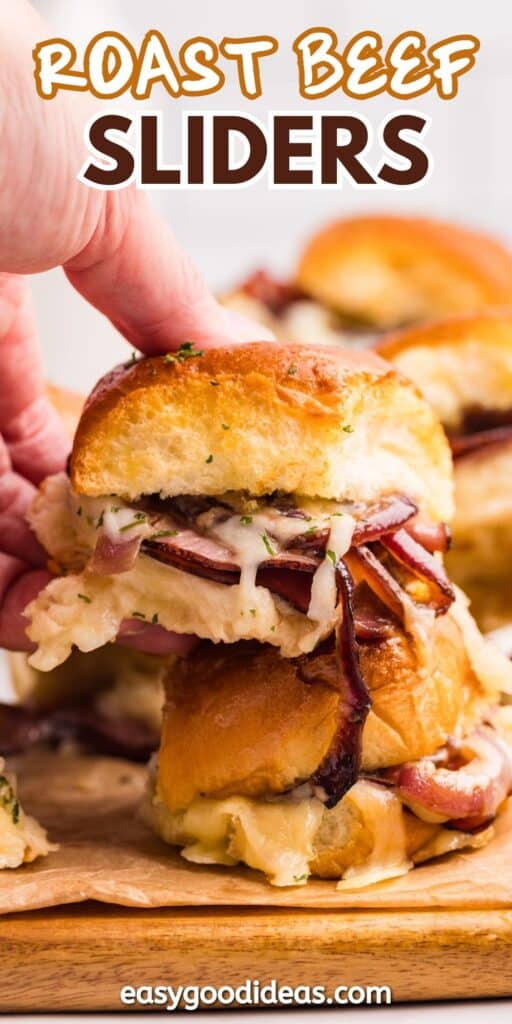 A hand lifts a roast beef slider made with a soft bun, roast beef, melted cheese, and onions, with more sliders stacked in the background. Text reads Roast Beef Sliders and easygoodideas.com.
