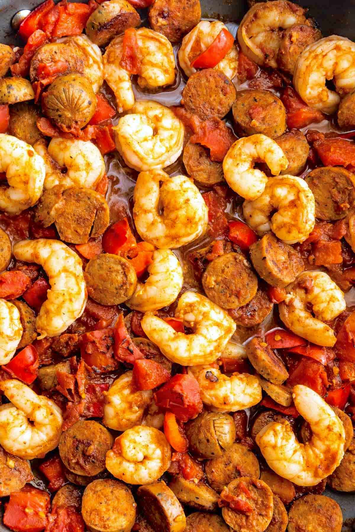 Shrimp and sliced sausage cooked with diced tomatoes and spices, creating a colorful, savory dish with a rich sauce.