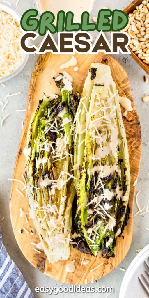 Two grilled romaine lettuce halves topped with Caesar dressing and shredded Parmesan cheese are served on a wooden platter, surrounded by pine nuts, extra cheese, and a bowl of dressing. Text reads “Grilled Caesar.”.