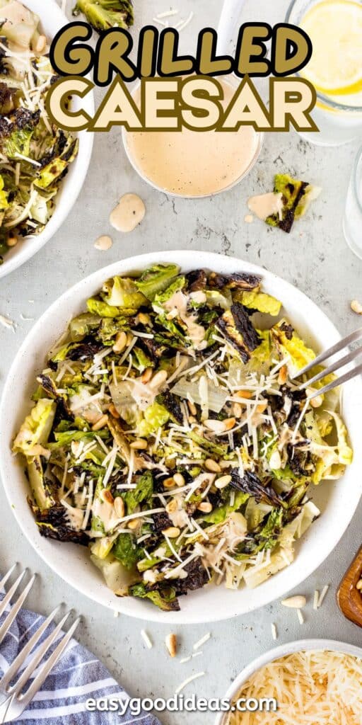 A bowl of grilled Caesar salad with charred romaine, shredded parmesan, dressing, and pine nuts. A fork rests in the bowl. The text Grilled Caesar appears at the top, with a website name at the bottom.