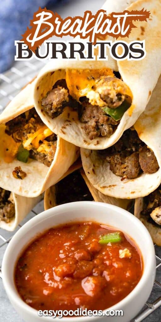 Three breakfast burritos filled with scrambled eggs, sausage, and cheese are stacked on a wire rack, with a bowl of chunky tomato salsa in front. Text at the top reads Breakfast Burritos.