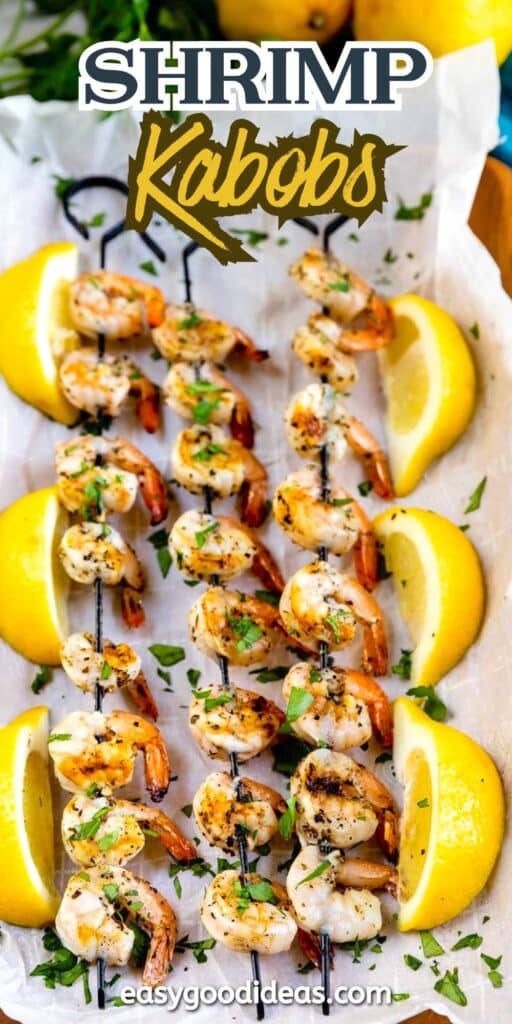 Grilled shrimp kabobs on skewers, garnished with chopped herbs, are served on parchment with lemon wedges. Text reads Shrimp Kabobs at the top and easygoodideas.com at the bottom.
