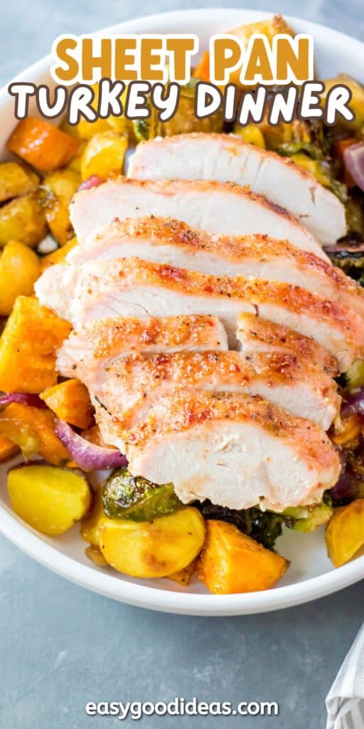 Sliced roasted turkey breast served on a white plate with golden roasted potatoes, Brussels sprouts, and red onions. The text on the image reads Sheet Pan Turkey Dinner.