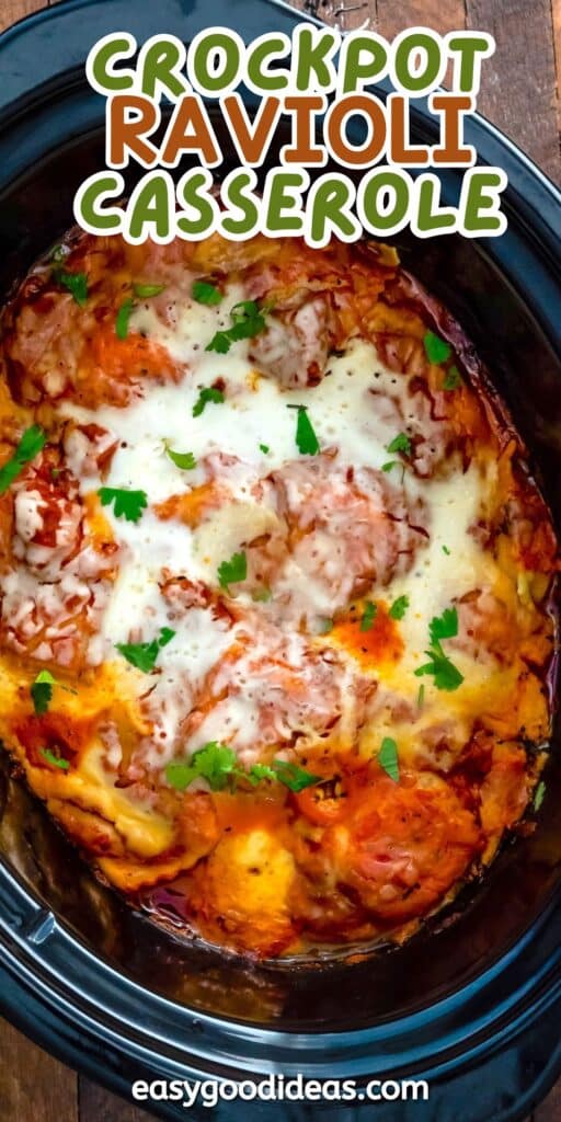 Overhead view of a cheesy crockpot ravioli casserole topped with melted cheese and chopped parsley, inside a black slow cooker. Text above reads “Crockpot Ravioli Casserole.”.