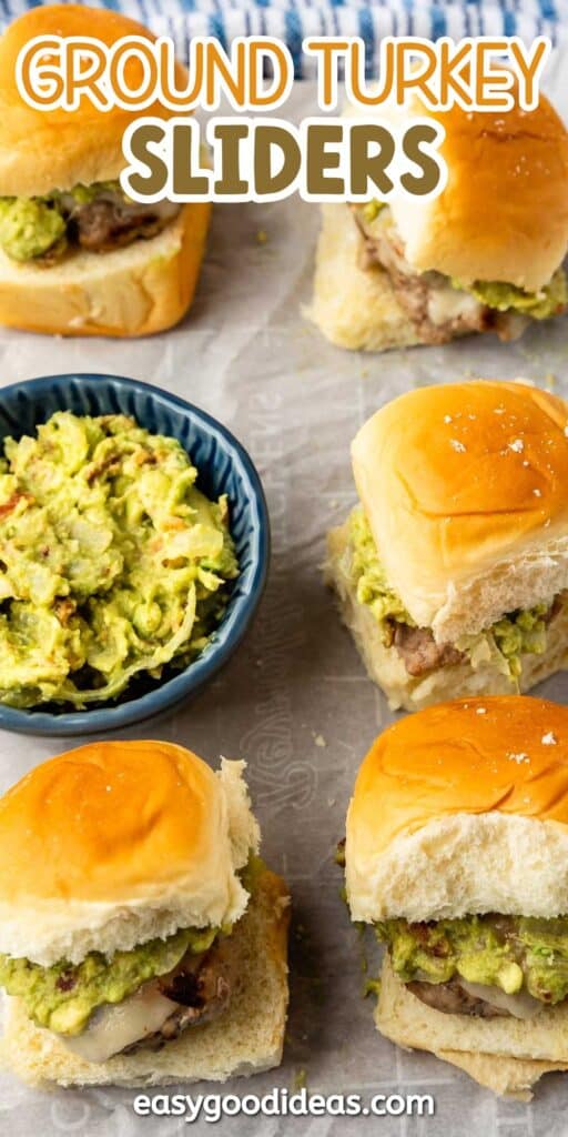 Four ground turkey sliders with melted cheese and guacamole on soft buns are arranged on parchment paper. A blue bowl with extra guacamole sits nearby. Text at the top reads “Ground Turkey Sliders.”.